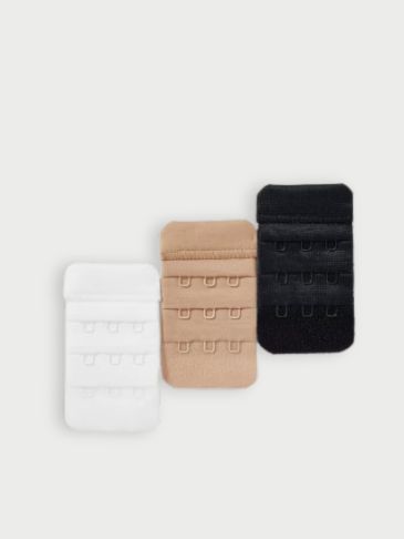 White, beige and black bra strap extenders on a light grey background